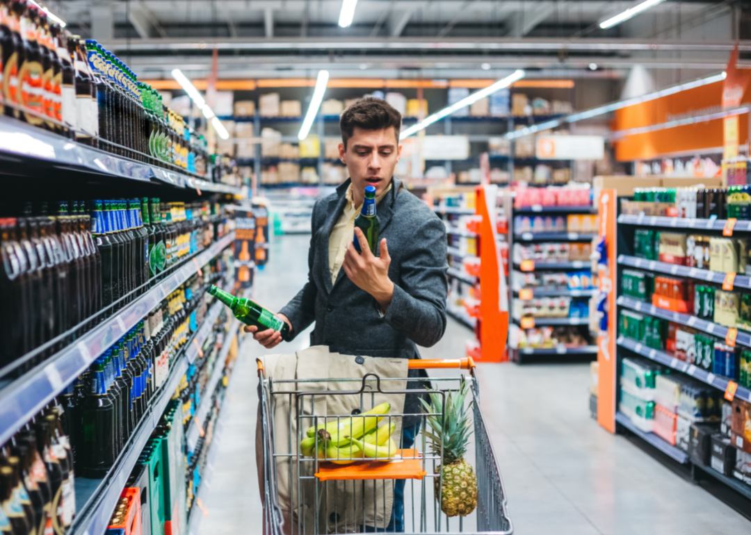 Shopper at grocery store looking at prices of items.