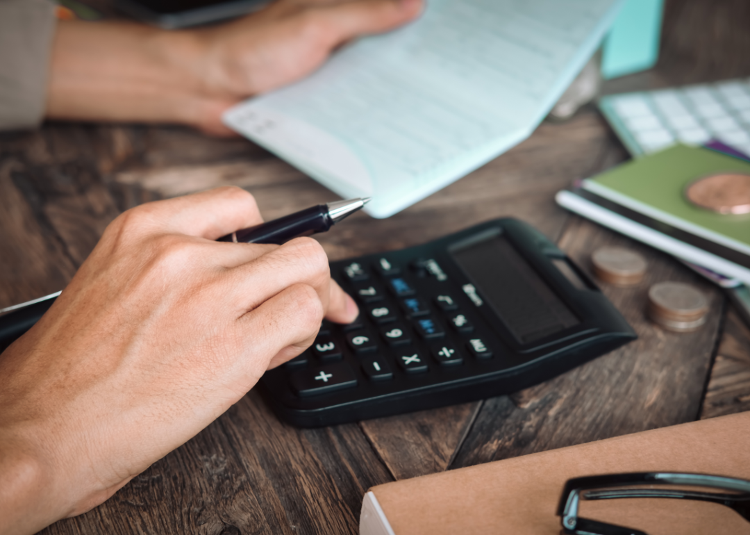 A personal holds a bill as they work on a calculator.