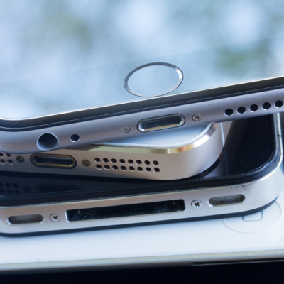 A close-up of a stack of smartphones on a desk.
