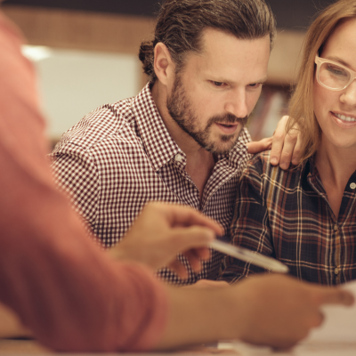 A couple reviews financial documents with a loan officer.