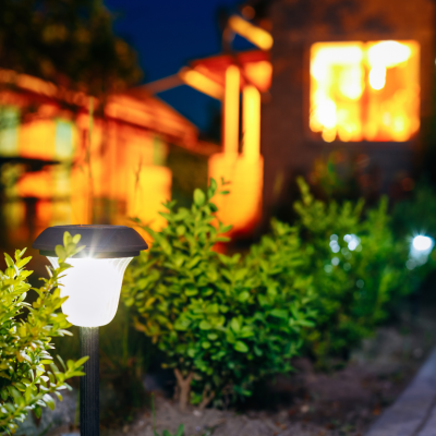 A solar powered light in a landscaped backyard at night.