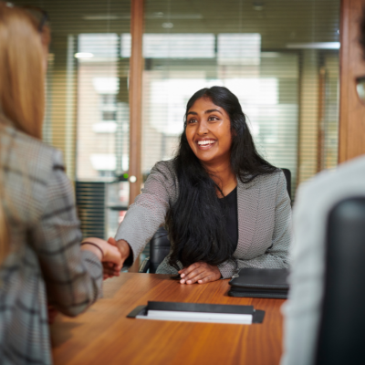 A woman smiling and shaking hands at a job interview