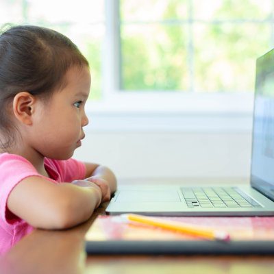 A young girl sits in front of a laptop