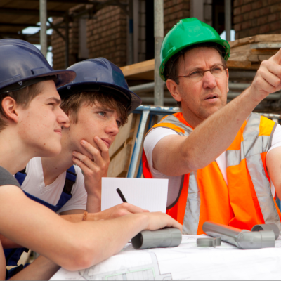 Two adolescent boys are fully focused on the level being held by their instructor. 