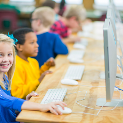 Kids in a computer lab sitting in front of desktop computers