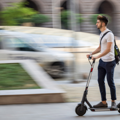 A man rides an e-scooter in a city