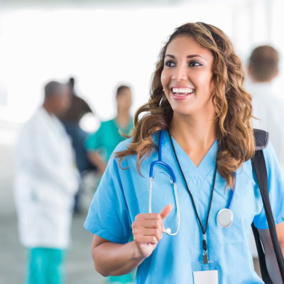 A female nurse with brown hair looking off-camera and smiling