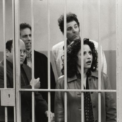 Actors Jason Alexander (George), Jerry Seinfeld (Jerry), Michael Richards (Kramer), and Julia Louis-Dreyfus (Elaine) stand behind bars in a scene from the final episode of 'Seinfeld.'