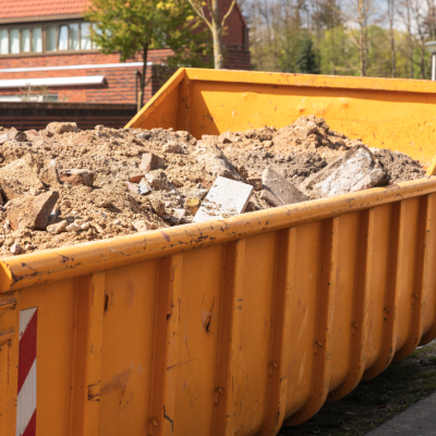 Debris from destruction of a building in a yellow container on a work site.