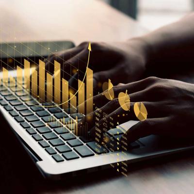person typing on computer with concept of financial graphs displayed