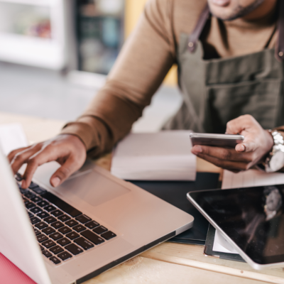 hands and arms of person using phone and laptop