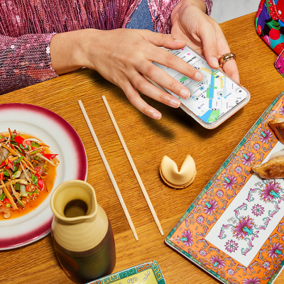 overhead photo of diner in front of chinese food meal while using lyft app on phone