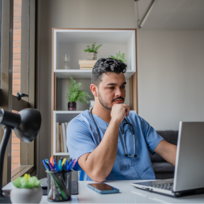 man wearing medical scrubs looking at computer in office