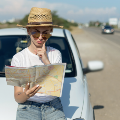 A woman reads a roadmap by the side of the road.