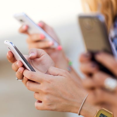 Close-up of several hands holding smartphones.