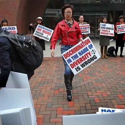 Ping Zhang holds a sign while demonstrating outside the John Joseph Moakley United States Courthouse on the opening day of Harvard University's affirmative action