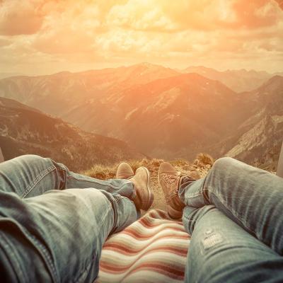 view from the trunk of a car of a sunset, legs of two people laying side-by-side visible 