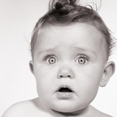 Wide-eyed baby from the 1950s looking at the camera.
