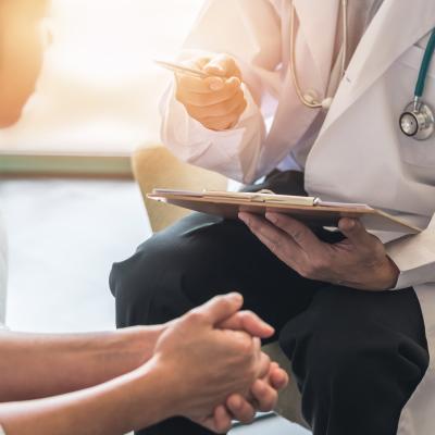 side profile of woman meeting with doctor holding clipboard 