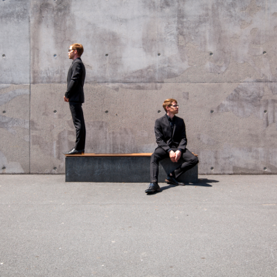 two people face away from each other in disagreement against stark gray concrete background