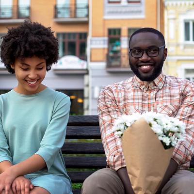 woman and man sit awkwardly on a bench on a date
