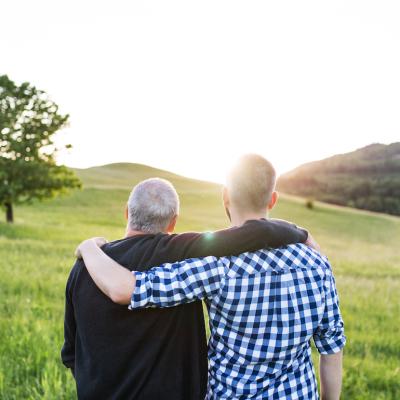 Two people stand with their arms around each other watching the sunset in rural America.