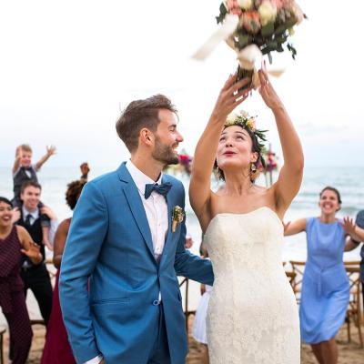 couple at wedding on the beach throwing bouquet