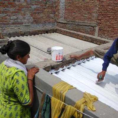 Residents of an informal settlement in India’s Ahmedabad city work on painting their home with sun-reflective white paint