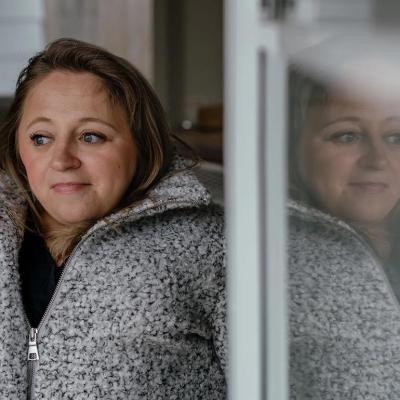 Portrait of Emily Voorde on left side with her image reflection visible on the glass on the right side