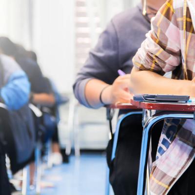 close up of students sitting at desks writing