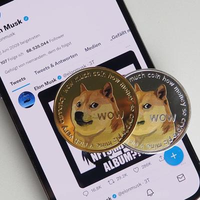 Two DOGE coin displayed on top of a smartphone with Elon Musk twitter profile open.