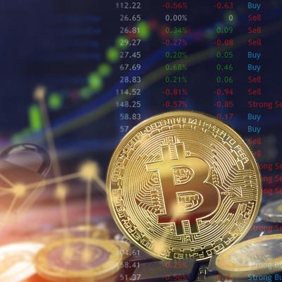 Bitcoin with stock market charts in background as concept of fluctuating cryptocurrrency values.