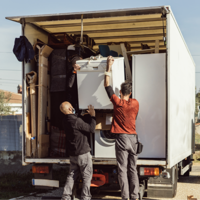 Two men loading up a moving truck with home furniture and appliances.