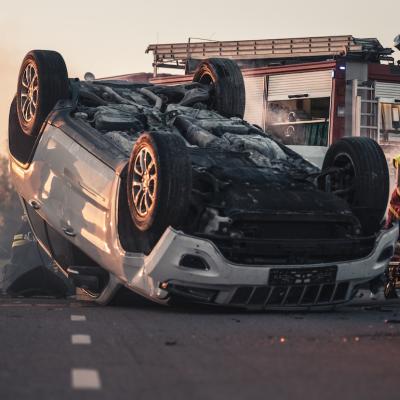 Burning vehicle upside down in the middle of the road after collision.