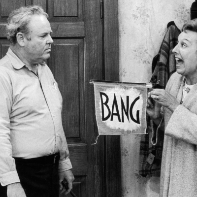American actor Jean Stapleton (right) points a toy gun with a flag that reads, 'Bang,' at American actor Carroll O'Connor (1924 - 2001), in a still from the season premiere of the television series 'All in the Family'. 