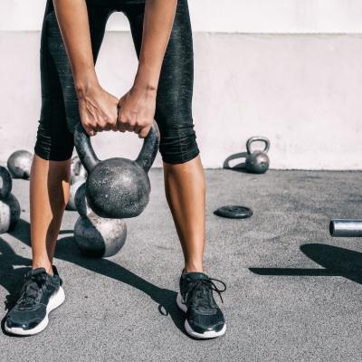 A person lifting a kettlebell weight at an outdoor gym.