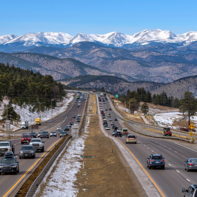  A sunny winter day view of busy Interstate Highway I-70, with snow-capped high peaks of the Continental Divide towering at west.