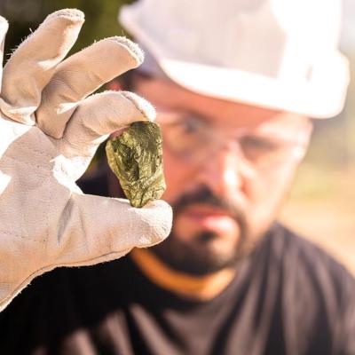 Miner holding gold nugget, with point focus on the gemstone.