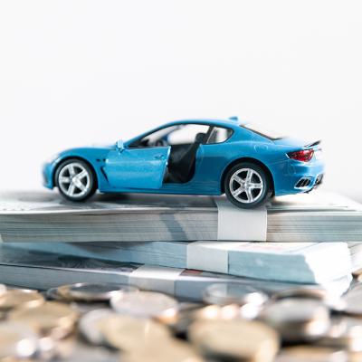 A blue car on top of a stack of money and coins.