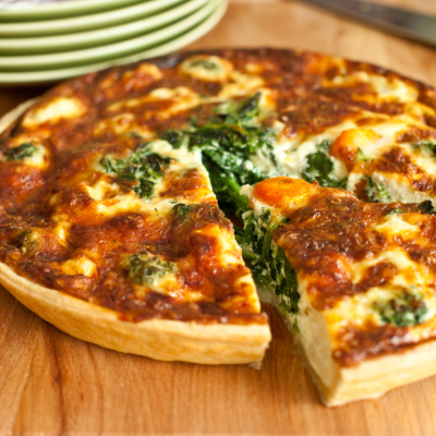 A freshly baked spinach quiche on a wooden kitchen counter