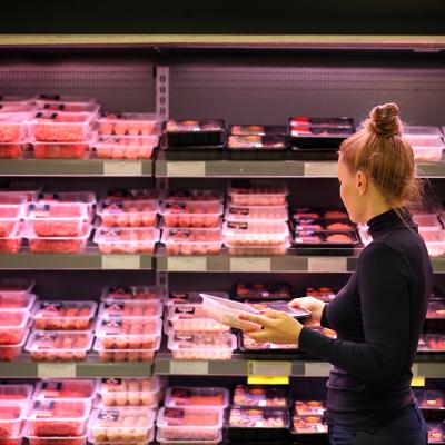 A woman shopping in the meat section of a supermarket.