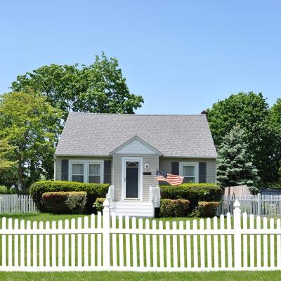 White picket fence in front of small bungalow house.