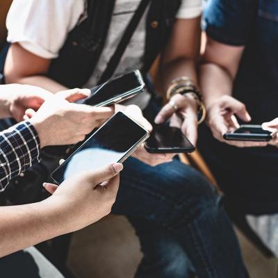 View of hands of group of young people using smart phones.