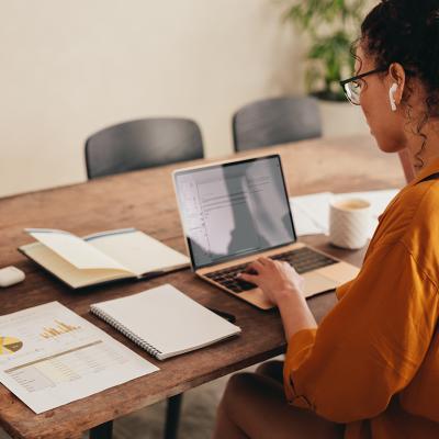 A busy young woman working from home with documents and notes in her table.