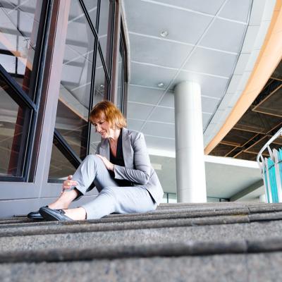 A woman at work sitting in pain after falling down the workplace stairs.