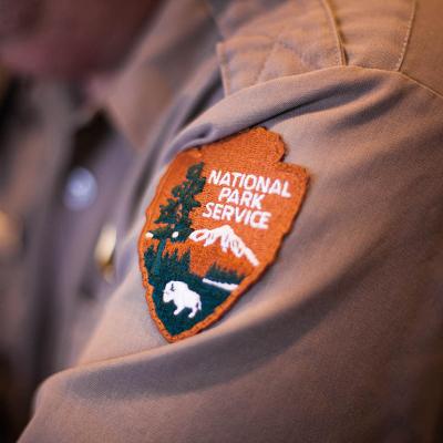 A closeup on the sleeve patch of a ranger's uniform showing the National Park Service logo.