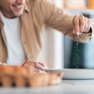 A man seasoning egg mixture with plenty of salt.