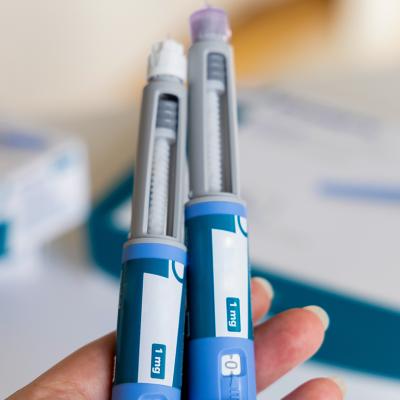 A hand holding two Ozempic pens for diabetics.