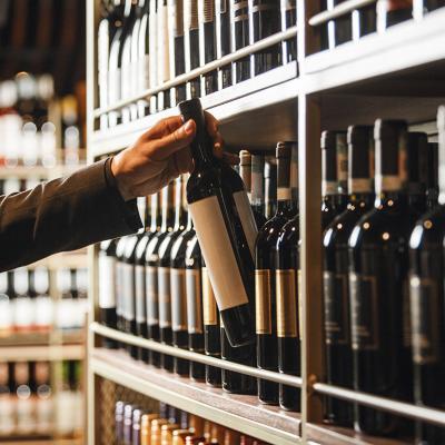 An extensive wine cellar collection and a wine bottle is being carefully picked.