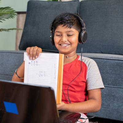 A kid virtually interacting with a tutor using a laptop.